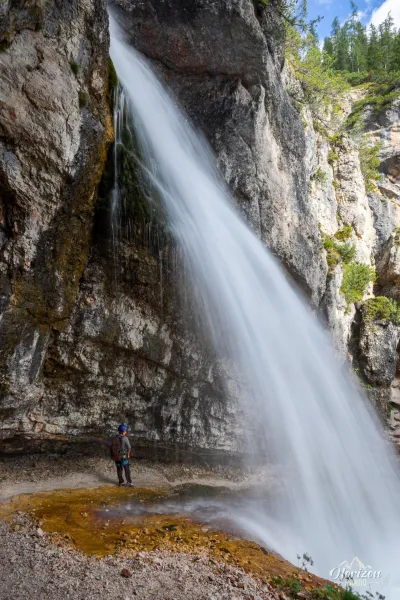 Passage en via ferrata derrière la chute de Fanes Randonneur en via ferrata derrière la cascade de Fanes, Dolomites