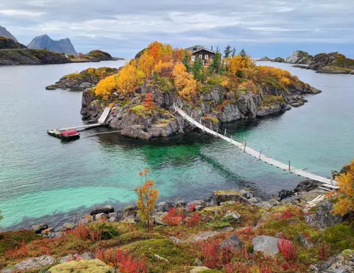 Maison sur un îlot relié par une passerelle aux couleurs d'automne à Hamn, île de Senja, Norvège